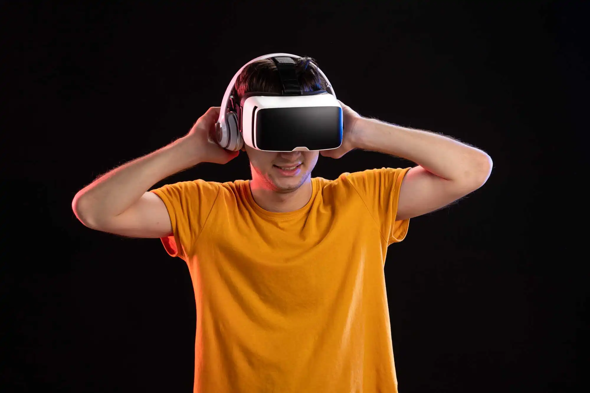 A person in an orange shirt smiles while wearing a virtual reality headset against a black background, conveying excitement and immersion